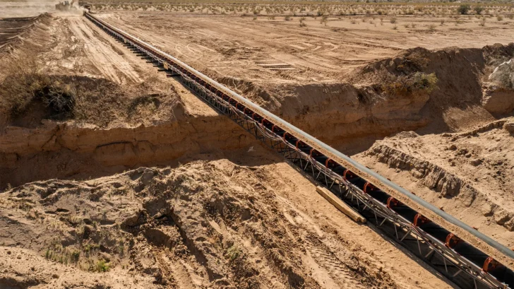 Groundline conveyor carrying material across excavated terrain