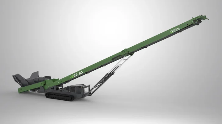 Side view of the Feeder Stacker showing the rear feed hopper, long conveyor, hydraulic support frame, and crawler tracks.